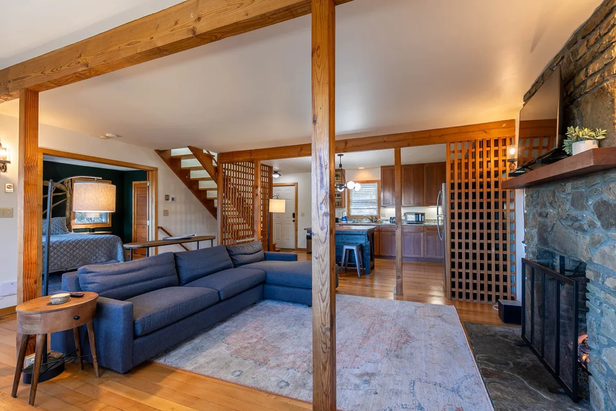 A cozy living room anchored by a plush sofa and a glowing fireplace, with a kitchen area visible in the background. The space feels intimate and welcoming, ideal for relaxing evenings together after a day of exploring.
