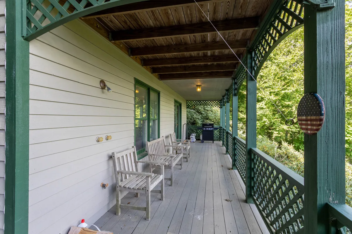 An exterior shot featuring a porch with chairs, a grill, and abundant greenery, fostering an atmosphere of outdoor relaxation and socializing. The inviting scene suggests opportunities for fresh air and shared moments with pets and family.