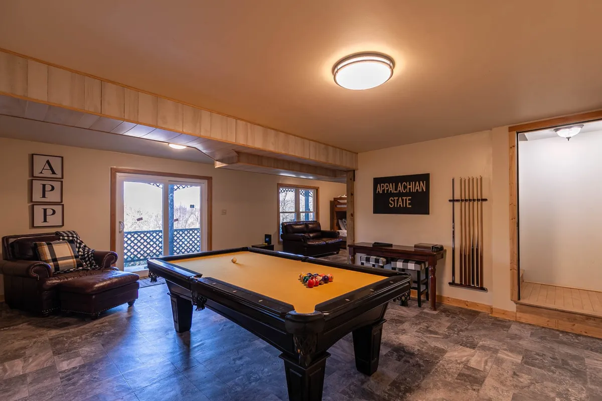 This image features a vibrant game room centered around an App State–themed pool table, with comfortable seating arranged close by and an Appalachian State sign enhancing the playful collegiate vibe. The space invites both friendly competition and socializing, perfectly embodying a family-friendly atmosphere.