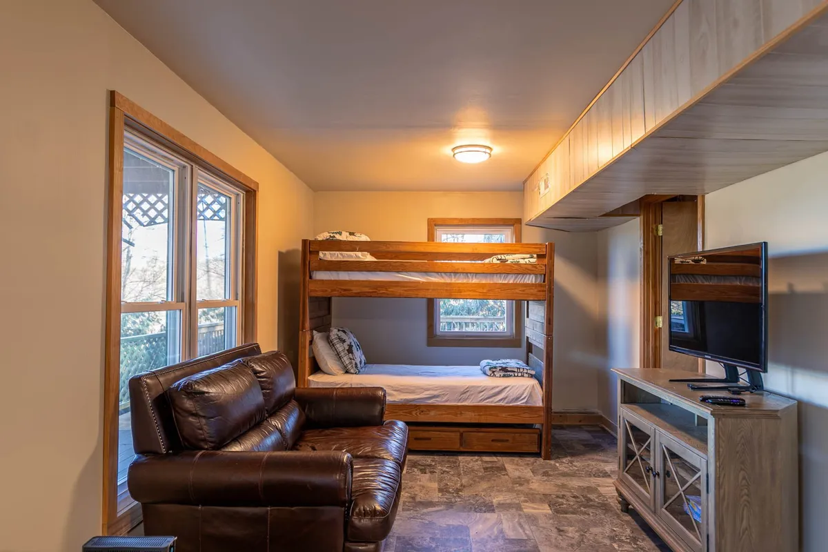 A cozy nook with twin-over-twin bunk beds, a leather couch, and a television, set in a welcoming and multi-functional space perfect for relaxing after gaming or hanging out with friends and family.